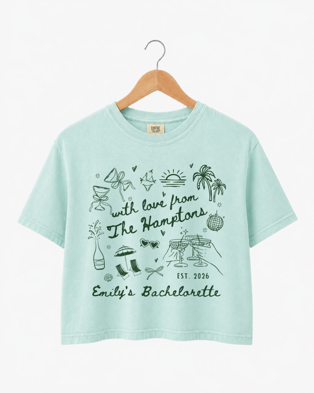 Gift idea for the bachelorette crew: Hamptons-themed crop top with playful illustrated doodles and script lettering. Personalized with bride name, destination, and weekend year for the whole party.