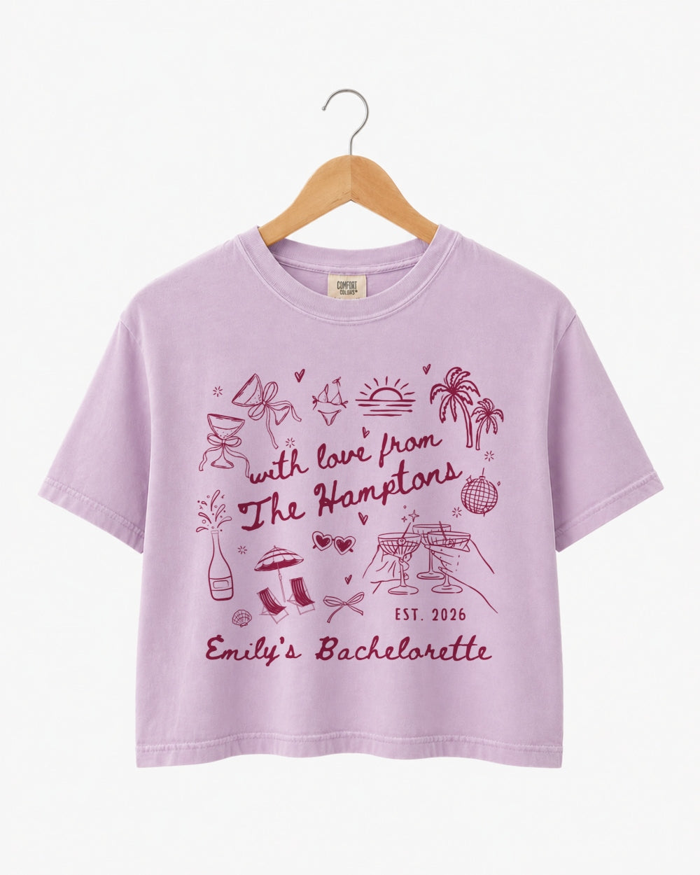 Bride and bridesmaids matching crop tops for a Hamptons bachelorette weekend. Playful illustrated doodle art with script lettering, personalized with bride name, date, and destination.