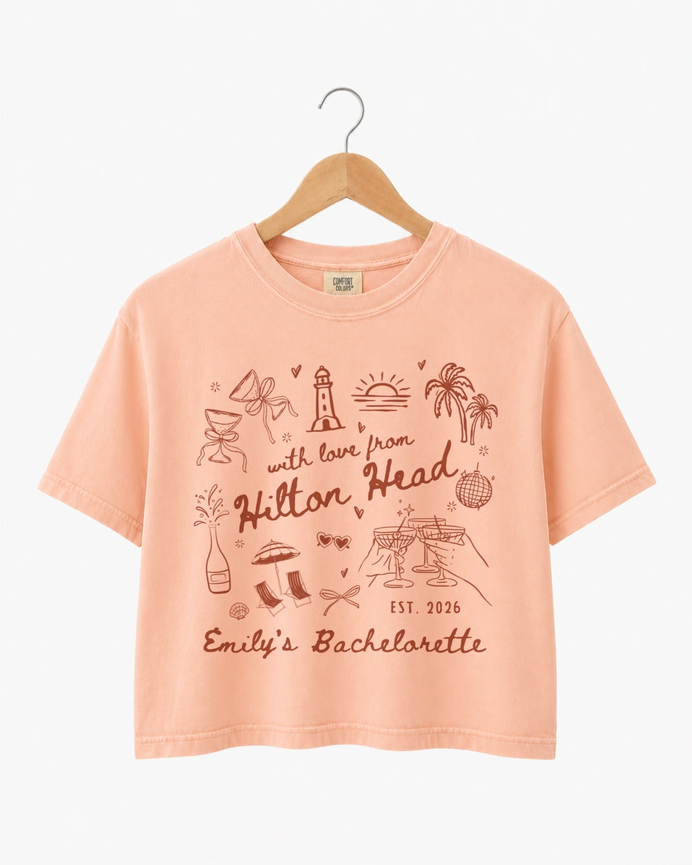 Playful line-art doodle bachelorette crop top with hand-drawn script and whimsical illustrations. Personalized with bride name, destination, and EST year for the whole bachelorette crew.