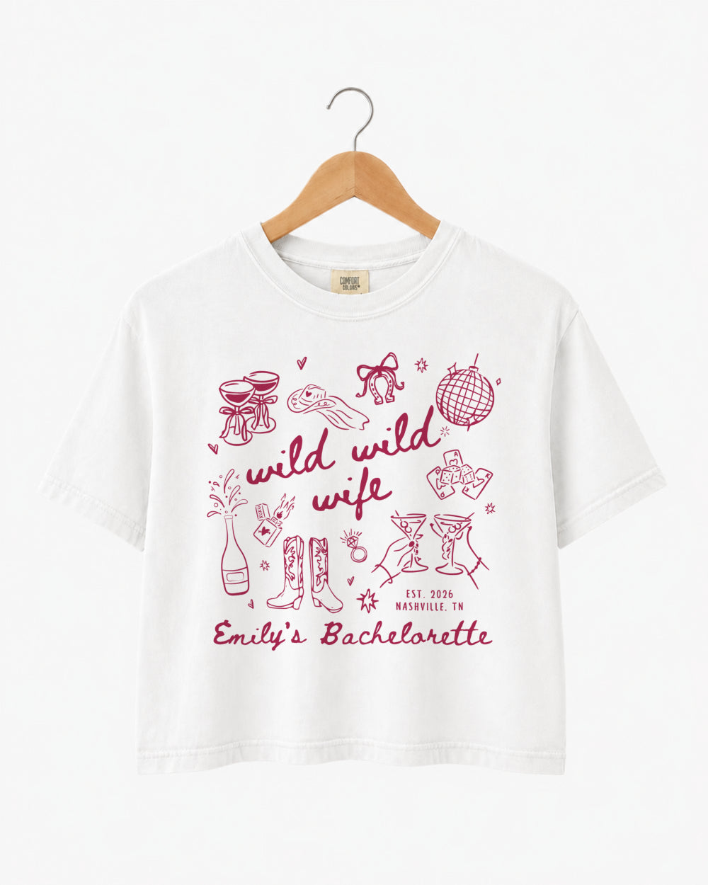 Boxy cropped bachelorette tee with playful doodle art and Wild Wild Wife script lettering for the bride and her crew. Personalize with bride name, date, and destination city.