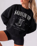 Bride and bridesmaid matching western bachelorette sweatshirts with vintage serif typography and saddlin up theme. Personalized with bride name, party destination, and year for the full crew.