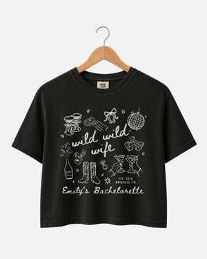 Bachelorette weekend crop top with Wild Wild Wife doodle art and script lettering. Personalized with bride name, EST year, and destination city for the whole crew.