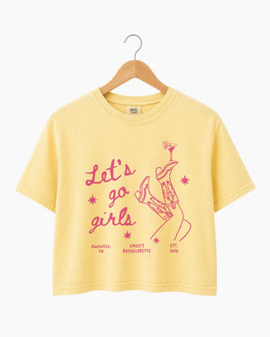 Personalized girls night out crop top with vintage line-art illustration of cowboy boots and martinis. Custom name or phrase on a Let's Go Girls bachelorette or girls trip tee.