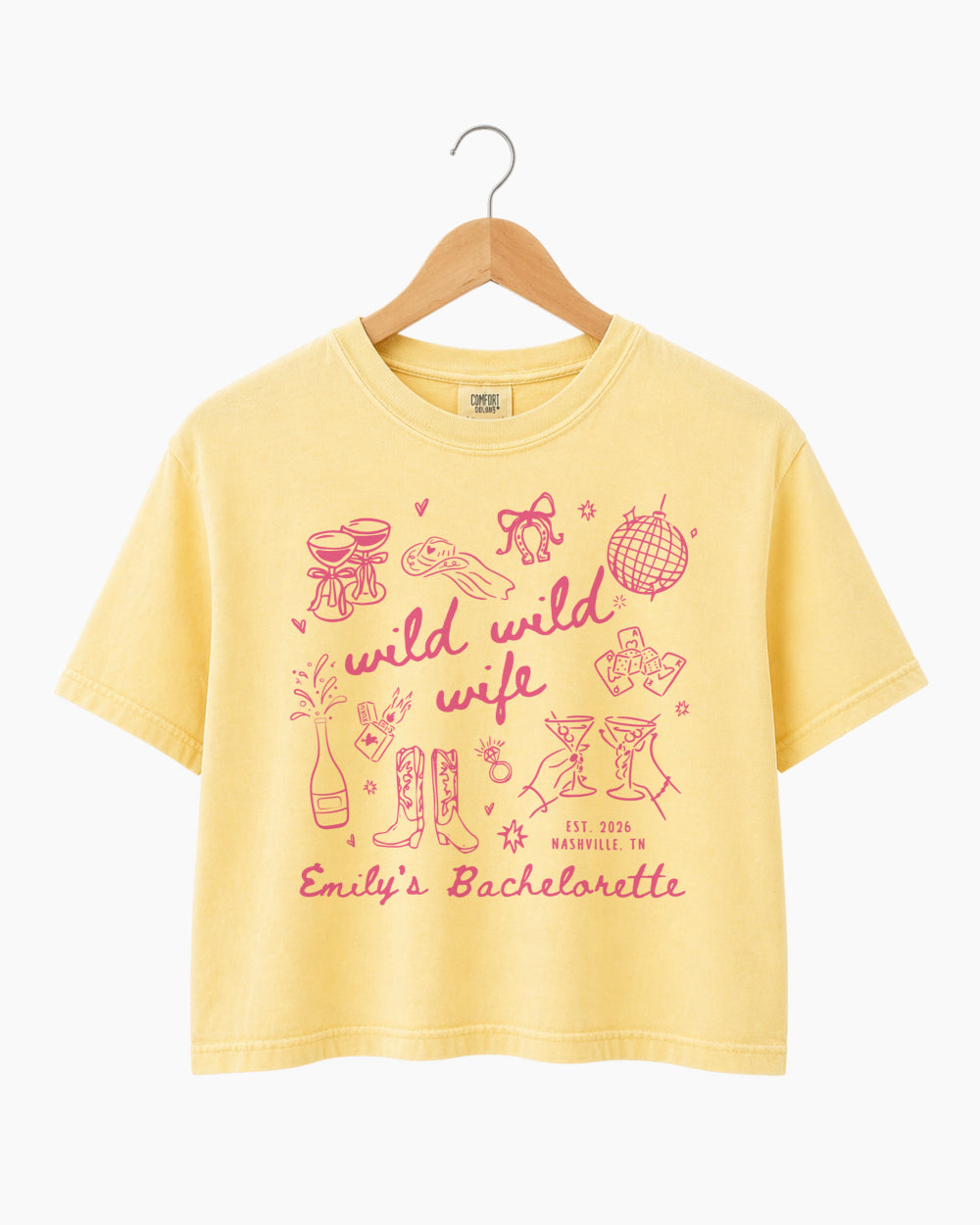 Personalized bachelorette crop top with bride name, date, and city on a Wild Wild Wife doodle design. Playful script lettering and line-art icons for the whole bachelorette crew.