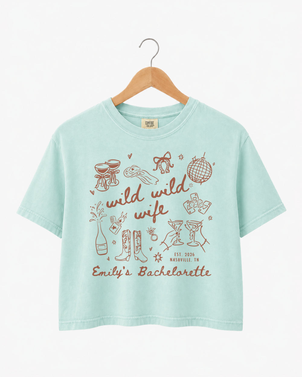Bride and bridesmaids matching boxy crop tees for a Wild Wild Wife bachelorette weekend. Personalized with bride name, EST year, and destination city for the full crew.