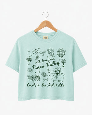 Gift idea for a Napa Valley bachelorette weekend: crop top with whimsical wine-country doodle art and script. Personalized with bride name, destination, and year for the whole crew.
