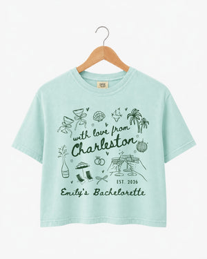 Gift idea for the bride-to-be: Charleston bachelorette crop top with hand-drawn doodle script and playful icons. Personalized with bride name, destination city, and EST year for the whole crew.