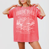 Watermelon red shirts for bachelorette camping, featuring a mountain design and "Last Trail Before the Veil" text for the bride-to-be