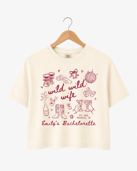 Bachelorette weekend crop top with Wild Wild Wife theme, playful line-art doodles, and script lettering. Personalized with bride name, EST year, and destination city for the whole crew.