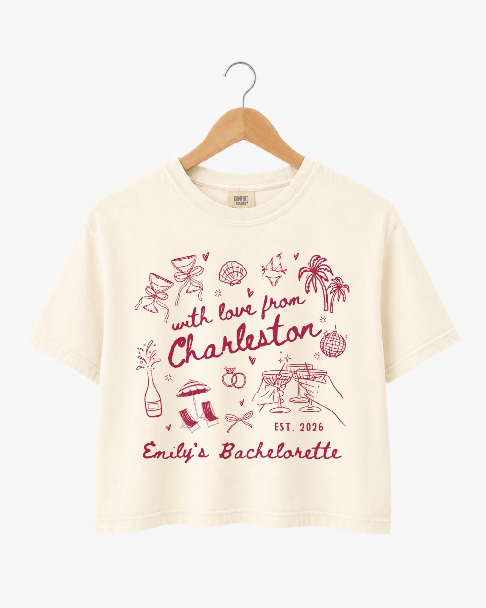Bachelorette weekend crop top with hand-drawn doodle script and playful icons for the Charleston bride and her crew. Personalized with bride name, destination city, and year.