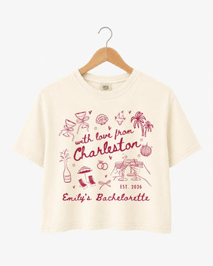 Bachelorette weekend crop top with hand-drawn doodle script and playful icons for the Charleston bride and her crew. Personalized with bride name, destination city, and year.