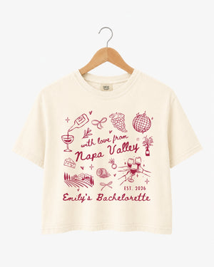Napa Valley bachelorette weekend crop top with whimsical wine-country doodles and script typography. Bride name, year, and destination customizable for the full bridal crew.