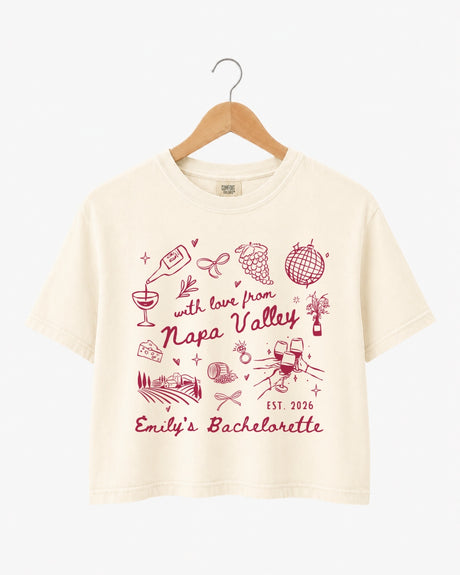 Napa Valley bachelorette weekend crop top with whimsical wine-country doodles and script typography. Bride name, year, and destination customizable for the full bridal crew.