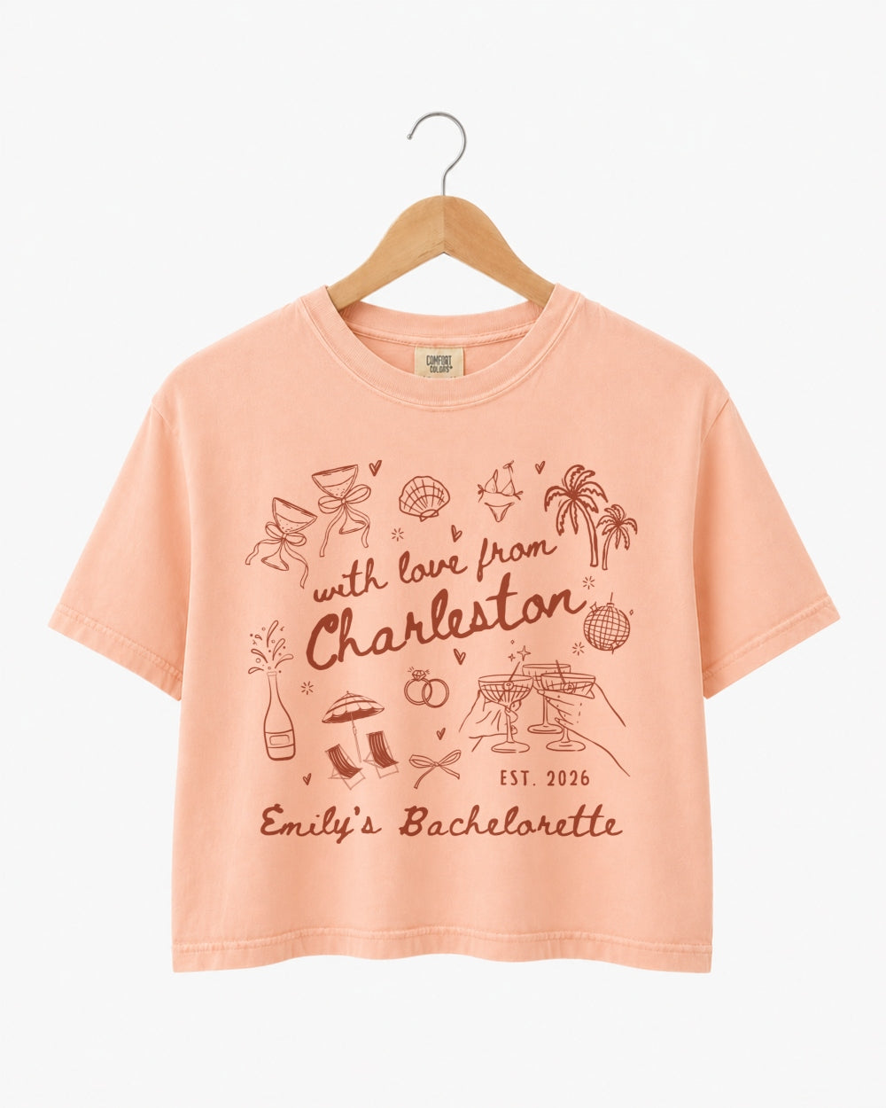 Hand-drawn doodle script bachelorette crop top with playful icons and a love-letter-to-the-city theme. Personalized with bride name, destination city, and EST year for the whole crew.