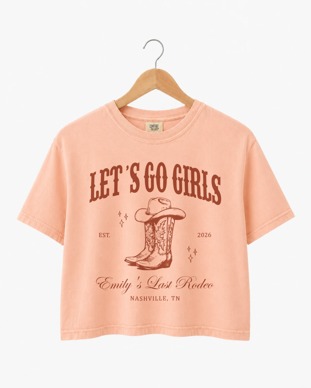 Vintage western script bachelorette crop top with cowboy boot illustration and rodeo theme lettering. Personalized with bride name, EST year, and destination city for the whole Nashville crew.