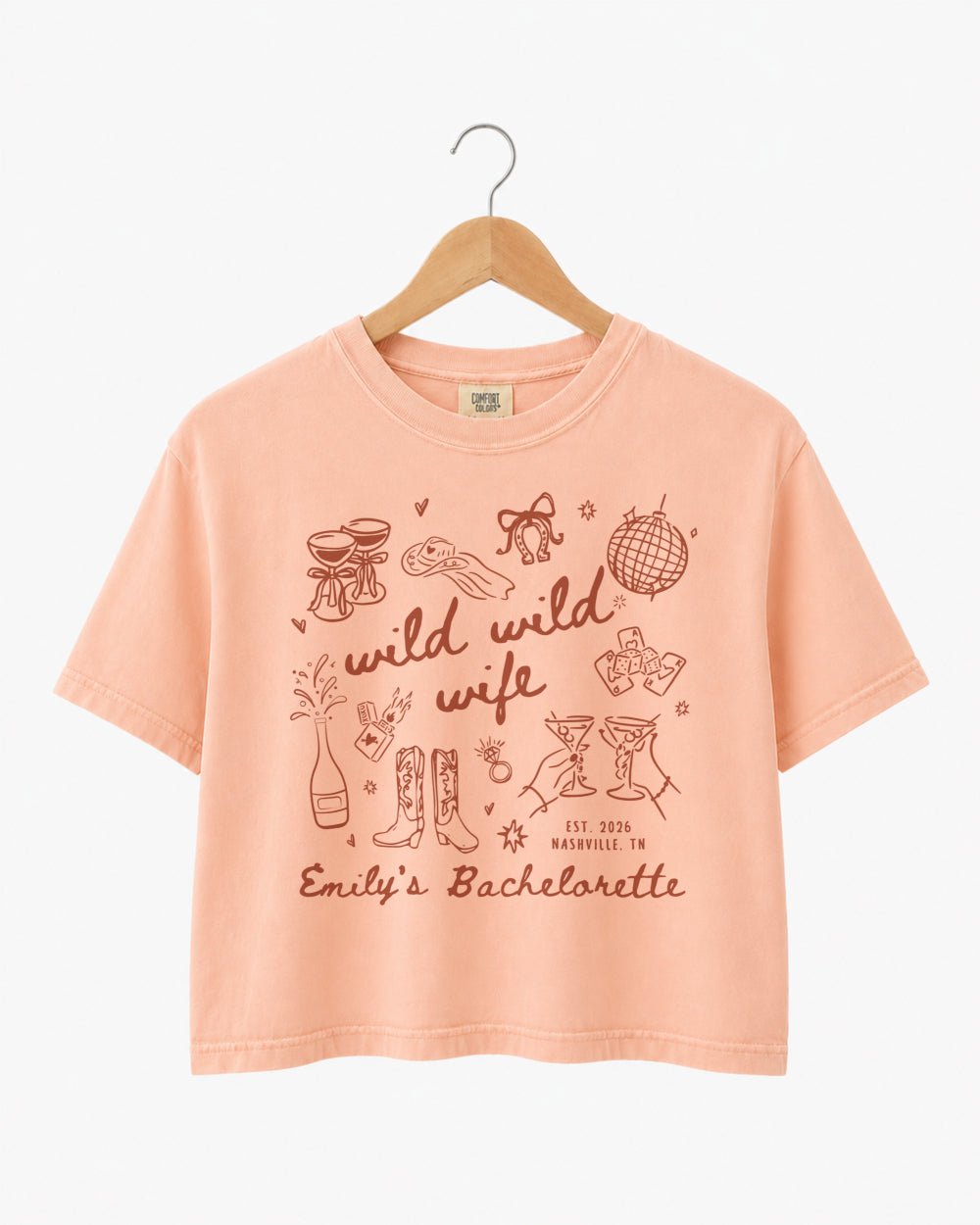 Playful doodle-art bachelorette crop top with Wild Wild Wife script lettering for the bride and her crew. Personalized with bride name, date, and destination city for a matching bachelorette weekend set.