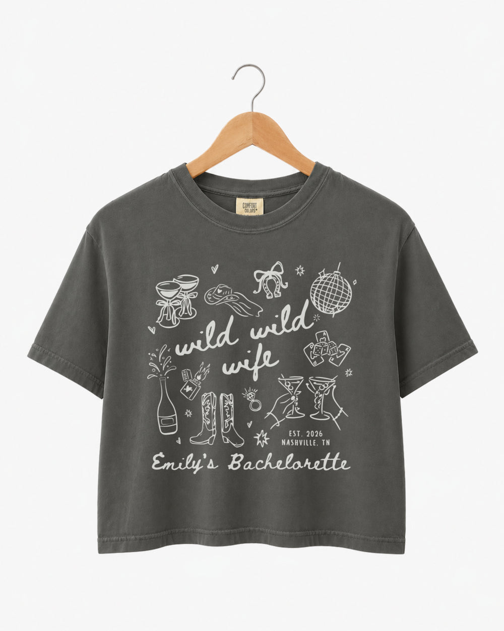 Matching shirts for the bachelorette crew with Wild Wild Wife script and playful line-art doodles. Personalized boxy crop top with bride name, date, and destination city for the whole party.
