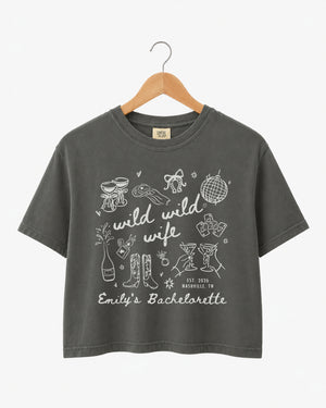 Matching shirts for the bachelorette crew with Wild Wild Wife script and playful line-art doodles. Personalized boxy crop top with bride name, date, and destination city for the whole party.
