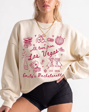 Personalized Las Vegas bachelorette sweatshirt with bride name, EST year, and destination city in playful doodle script. Matching crew customization for the whole bachelorette party.