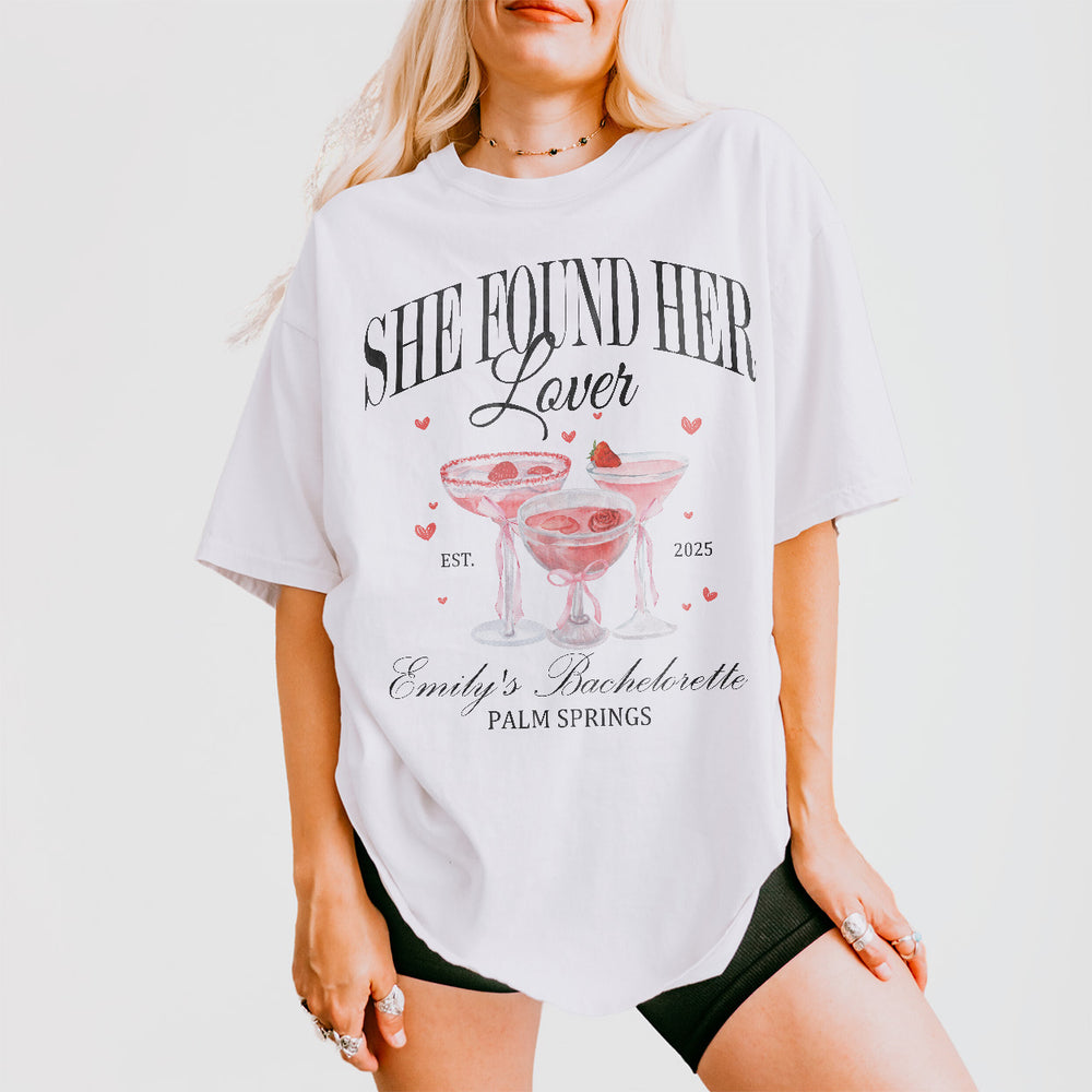 White bachelorette party shirt for bride's friends and bridesmaids with "She Found Her Lover" slogan for girls trip or cocktail club celebration