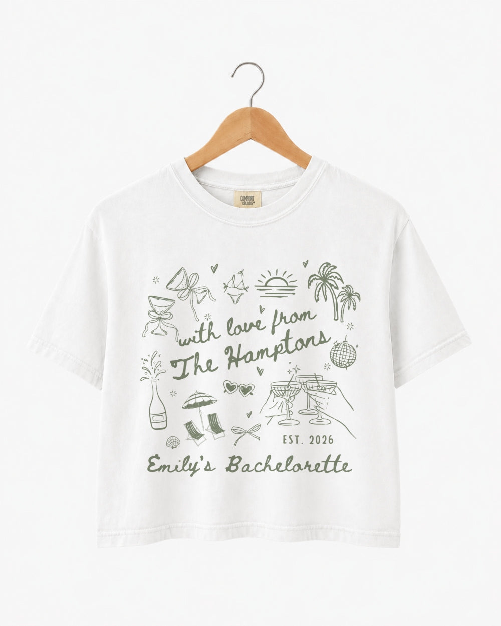 Bachelorette weekend crop top with Hamptons theme, playful illustrated doodles, and script text. Personalized with bride name, year, and destination for the whole crew.