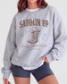 Gift idea for the bachelorette crew: western-theme sweatshirt with vintage serif lettering and Saddlin' Up script. Personalized with bride name, party date, and destination city.